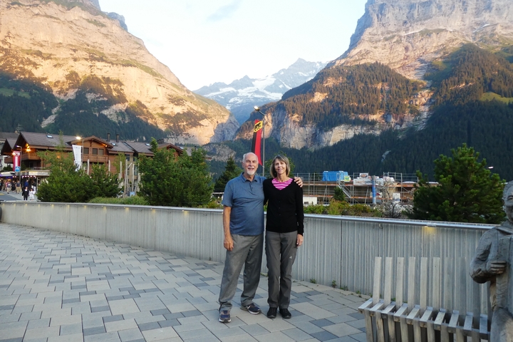       A couple posing with a mountainous backdrop in a small village.
  
