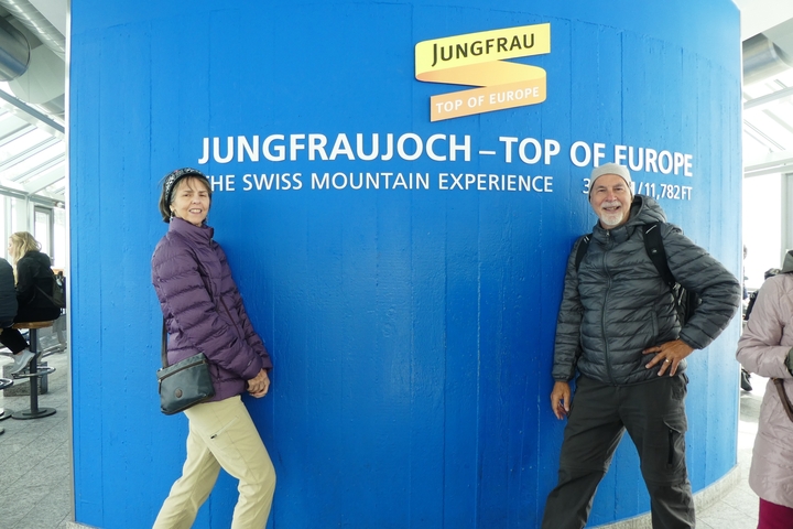 A couple at Jungfraujoch, the Top of Europe sign with a mountainous backdrop.