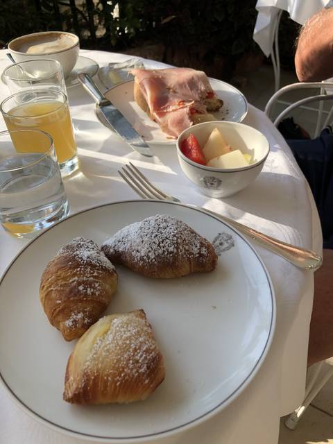       Breakfast setting with croissants, ham sandwich, and fruit.
  