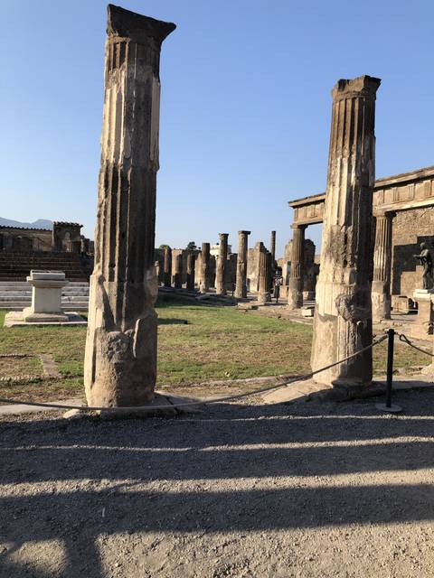       Ancient ruins with numerous columns under blue sky.
  