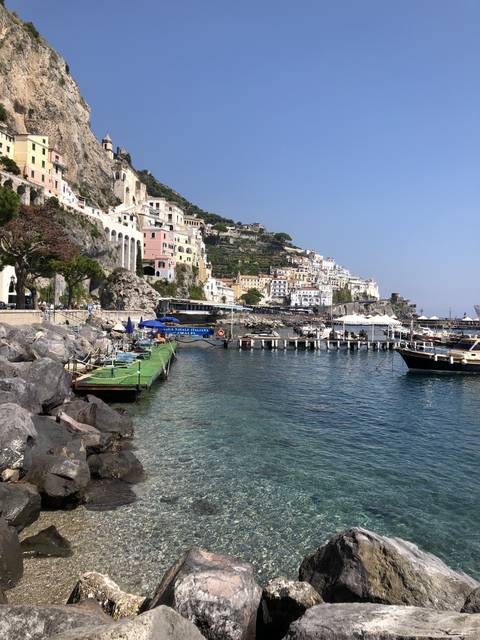       Seaside view with colorful buildings on cliffs.
  