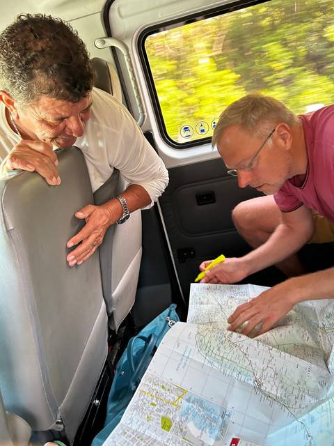       People looking at a map inside a vehicle.
  