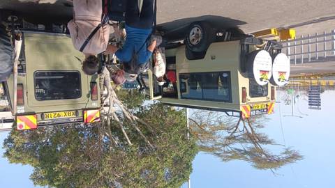       People gathering around a safari vehicle.
  