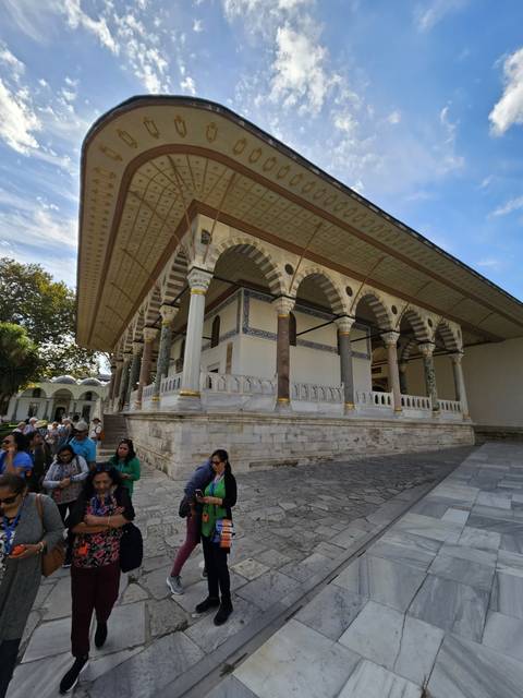       Group exploring a historical building with columns and intricate ceilings.
  