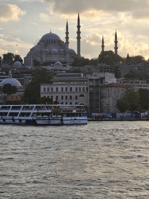      Silhouette of a mosque and a cruise boat at sunset.
  