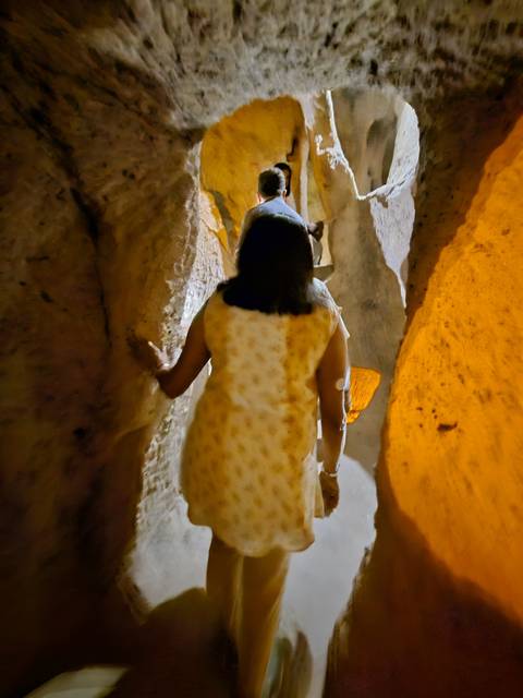       Person exploring an illuminated underground passage.
  