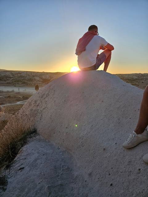       Person sitting on a rock watching the sunset.
  