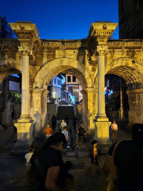       People walking through an ancient archway at night.
  