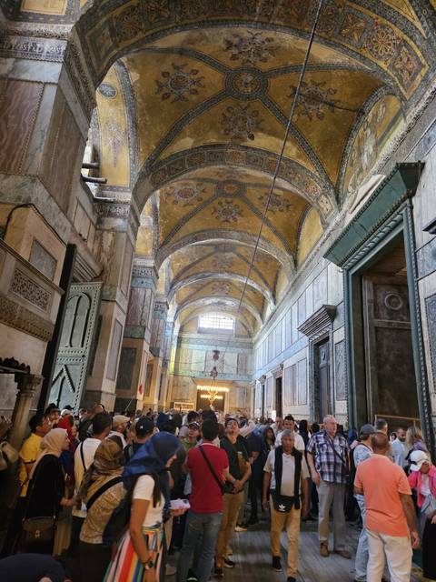      Interior of a historical building with tourists.
  