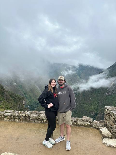 Two people posing on a mountain path with foggy background.