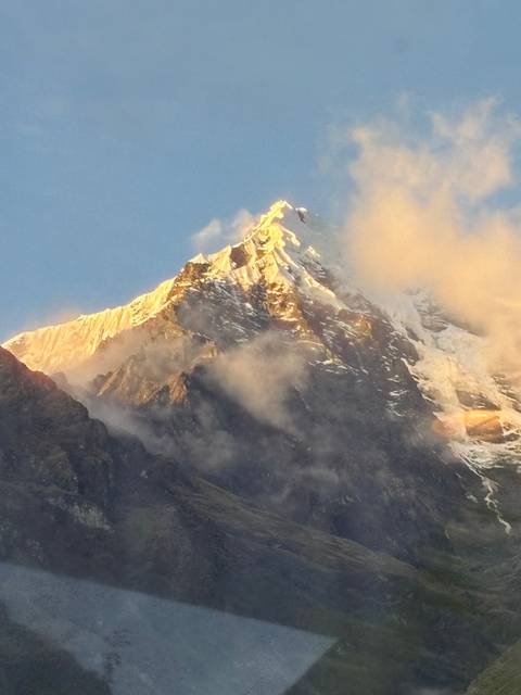       Mountain peak covered with snow and clouds.
  