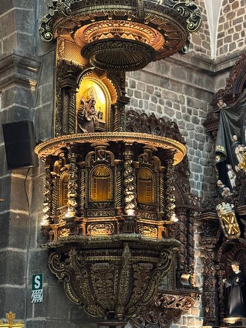       Ornate gold and wooden religious structure within a stone setting.
  