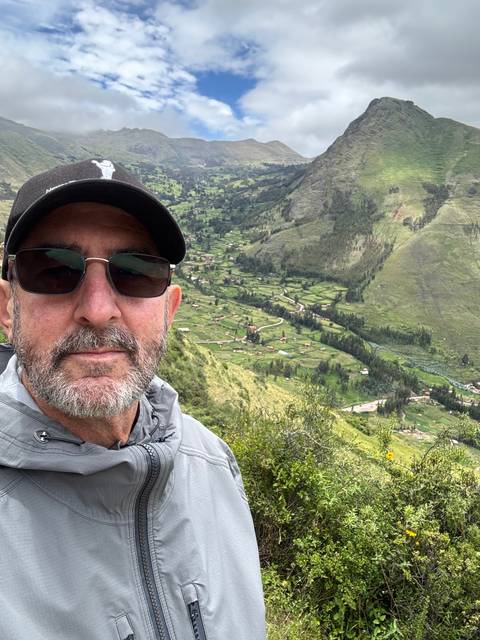      Person taking a selfie with a scenic valley in the background.
  