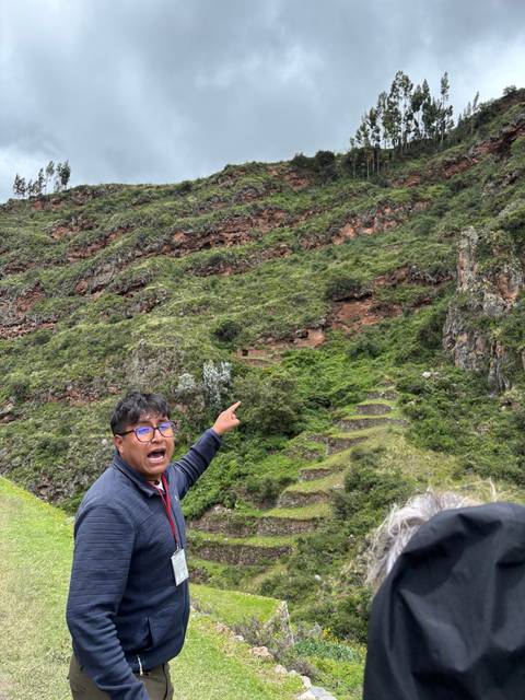       Person pointing towards a mountain while talking.
  