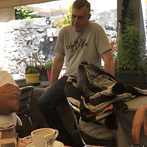 Person sitting at a table with a backpack beside him.