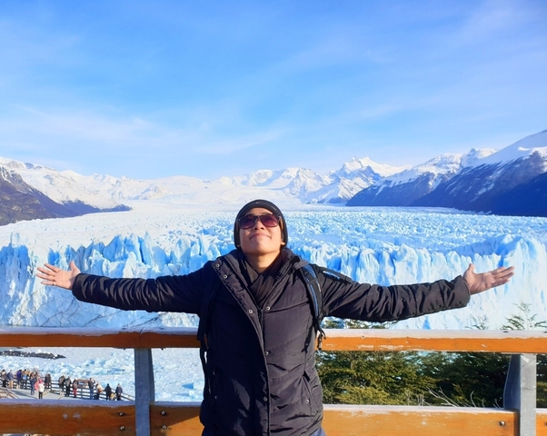 Person with outstretched arms in front of Perito Moreno Glacier.