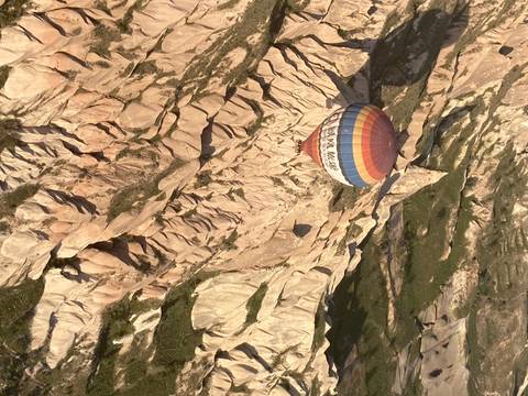 Hot air balloon flying over a rocky landscape.