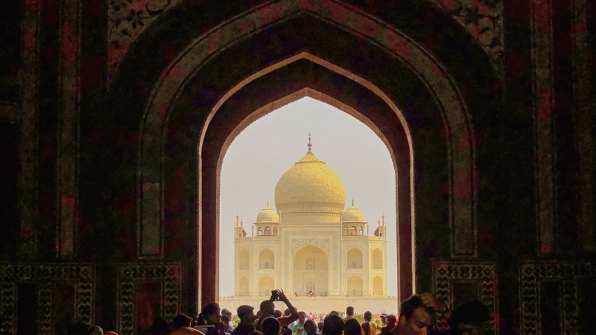 Taj Mahal framed by an arch with a crowd.