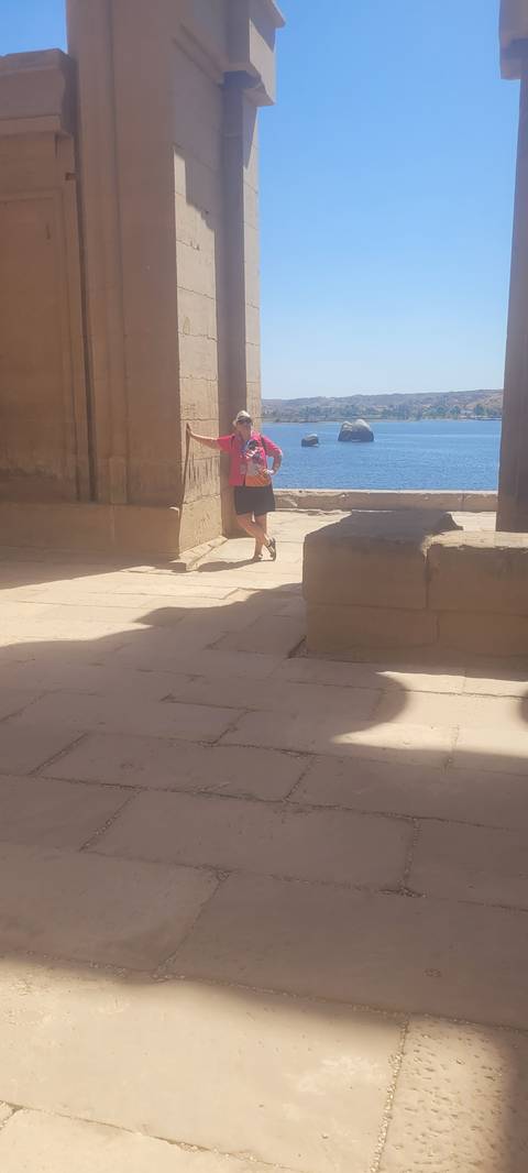 Person standing inside a historical site area with a bright view outside.