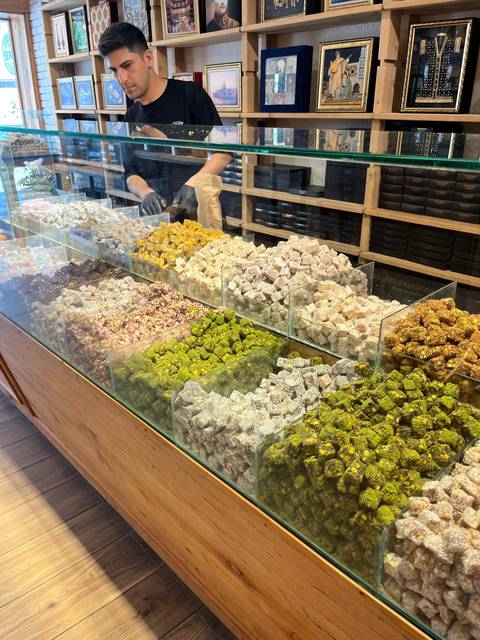       Assorted colorful sweets displayed in glass cases in a market.
  