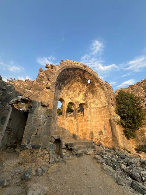       Ancient stone archway ruins lit by warm sunlight.
  