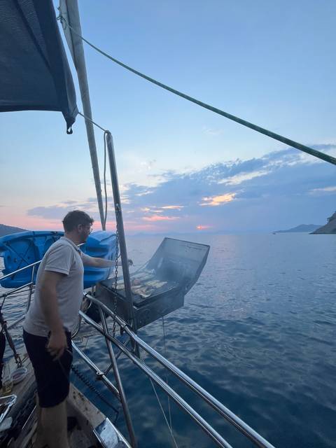       Person cooking on a boat during sunset.
  