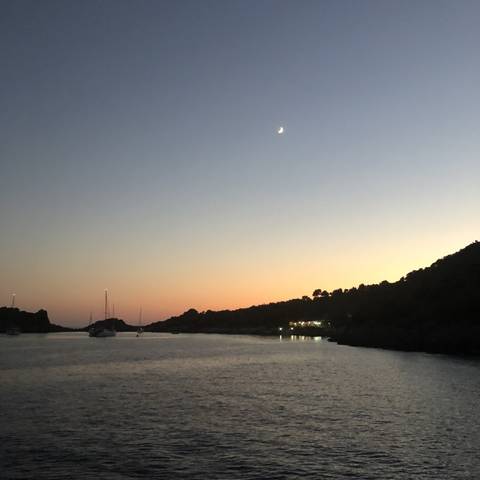       Sunset view over water with visible horizon and moon.
  
