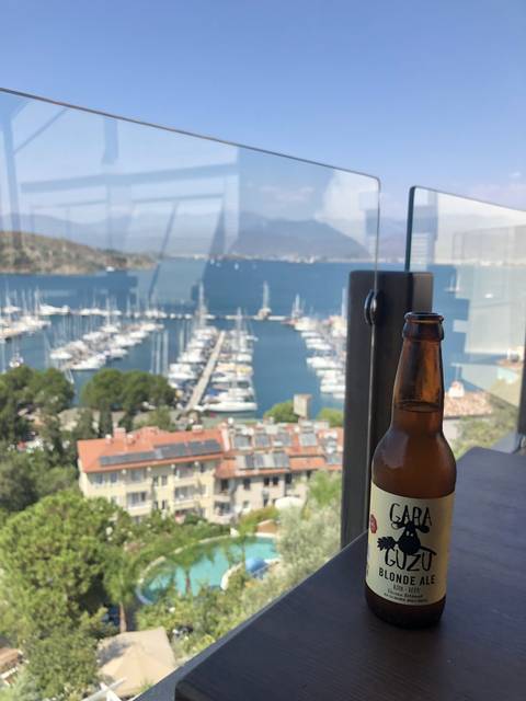       A bottle of drink overlooking a marina and houses.
  