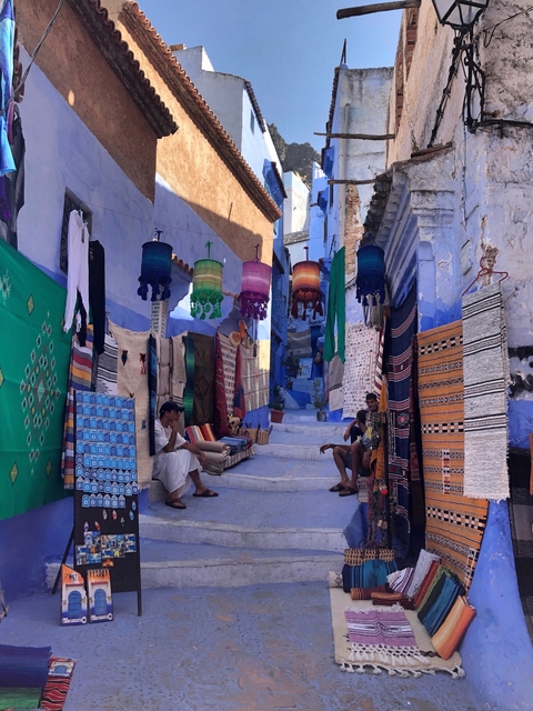       Street in Chefchaouen lined with colorful textiles and decor.
  