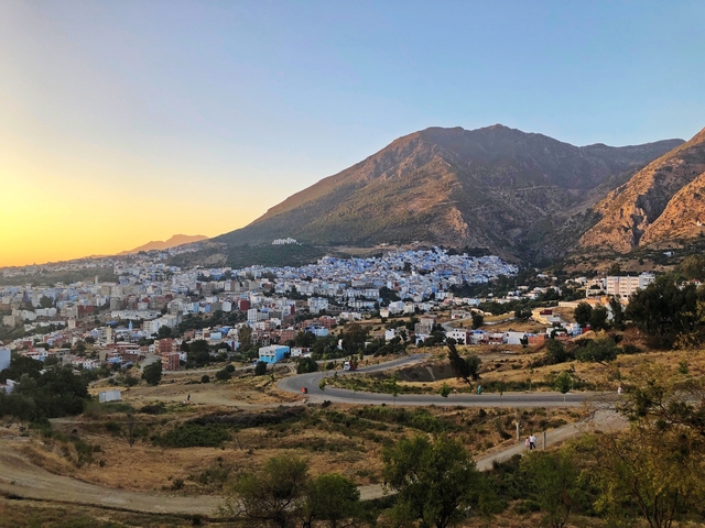 Panoramic view of Chefchaouen city surrounded by mountains at sunset.