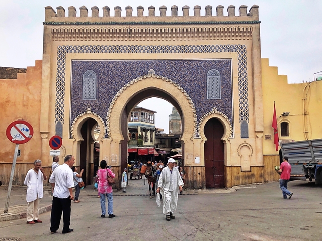 Bab Bou Jeloud gate in Fes with pedestrians and vibrant tiles.