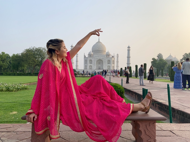       Person in traditional clothing posing with the Taj Mahal in the background.
  