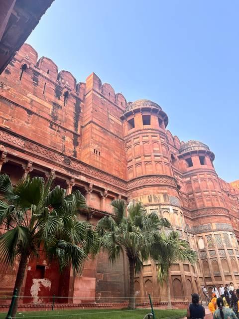 Red sandstone Mughal fort with palm trees.