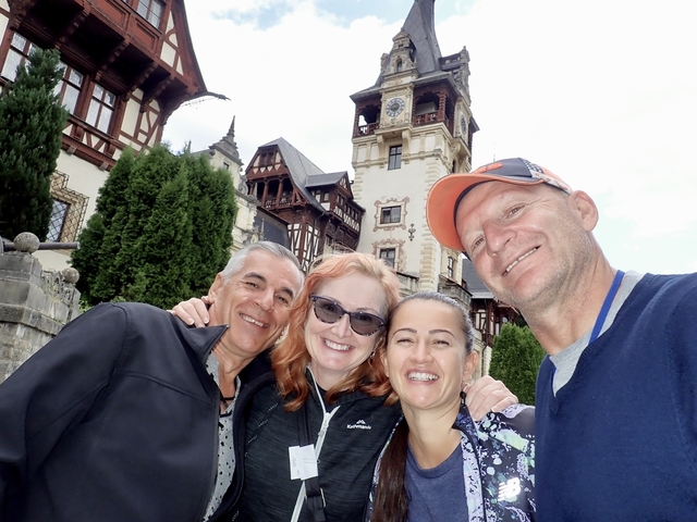 Group of four people smiling in front of Peles Castle.
