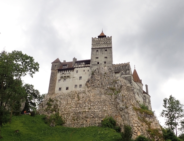 Bran Castle perched on a rocky hill with cloudy skies.