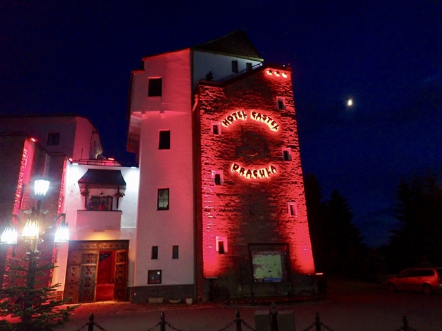 Brightly lit hotel exterior with a moon in the night sky.