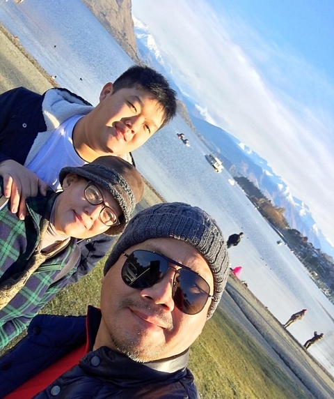 Group selfie with a scenic lake and mountains in the background.