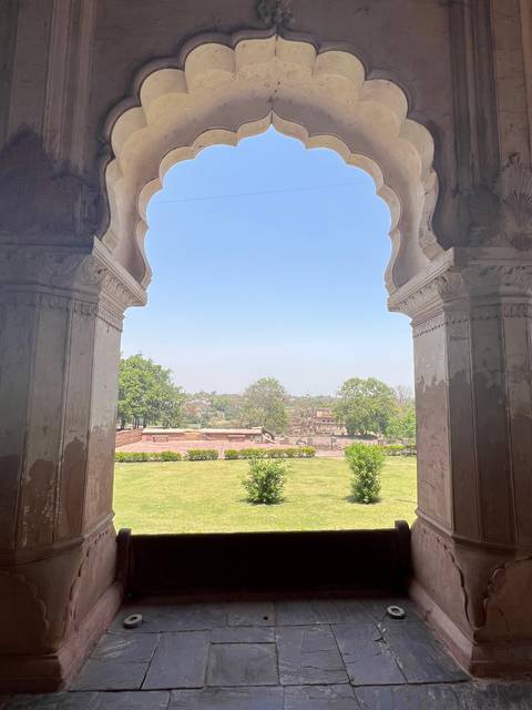 Archway with scenic view of gardens and sky.