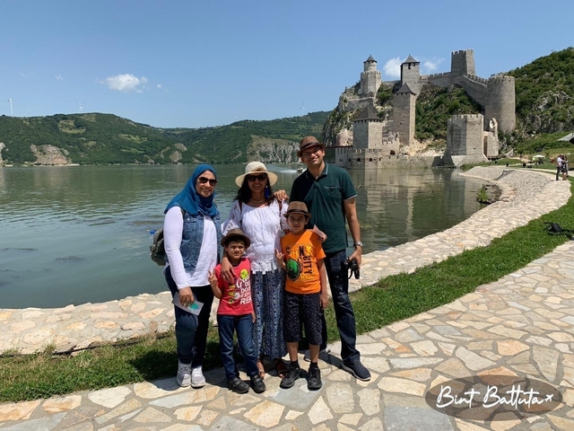       Family posing in front of a waterside fortress.
  
