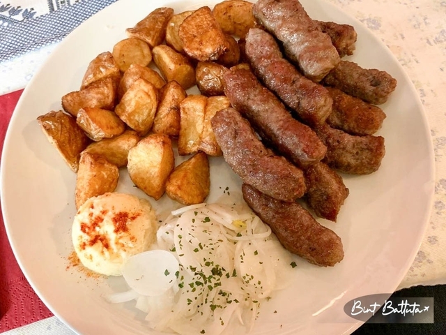       A plate of traditional Serbian food with cevapi and potatoes.
  