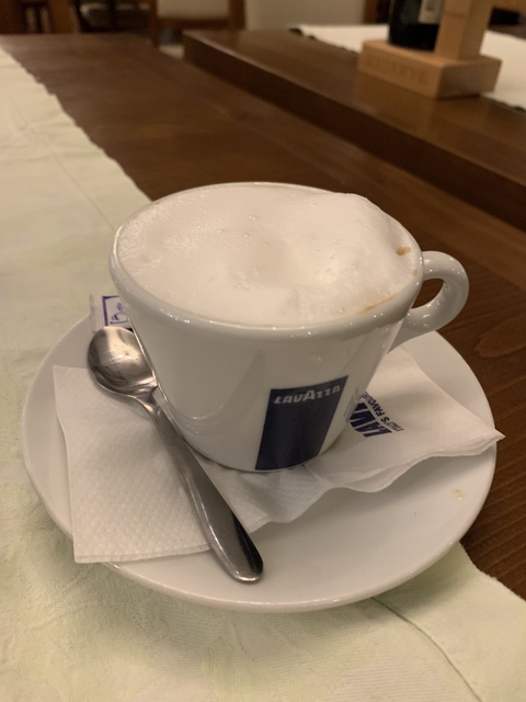       Cappuccino coffee cup with foam and a spoon on a napkin.
  