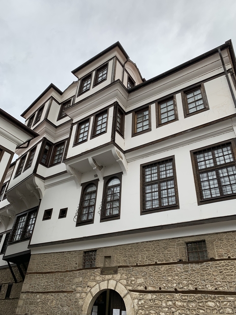       Facade of a traditional white building with brown window frames.
  