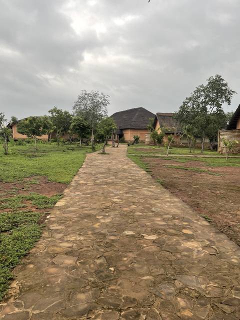       Pathway leading to a thatched building.
  