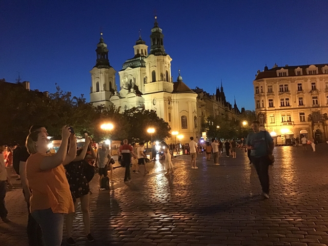People enjoying an evening in a European city with a lit church facade.