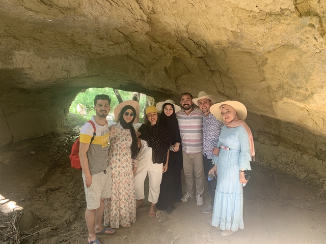Group posing inside a rock formation, smiling and wearing hats.