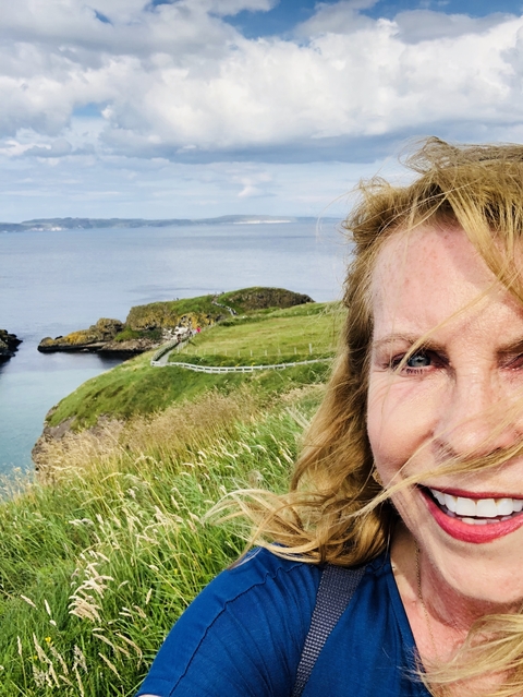       Close-up of a woman with a scenic coastal background.
  