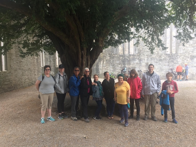       Group of people posing under a large tree.
  