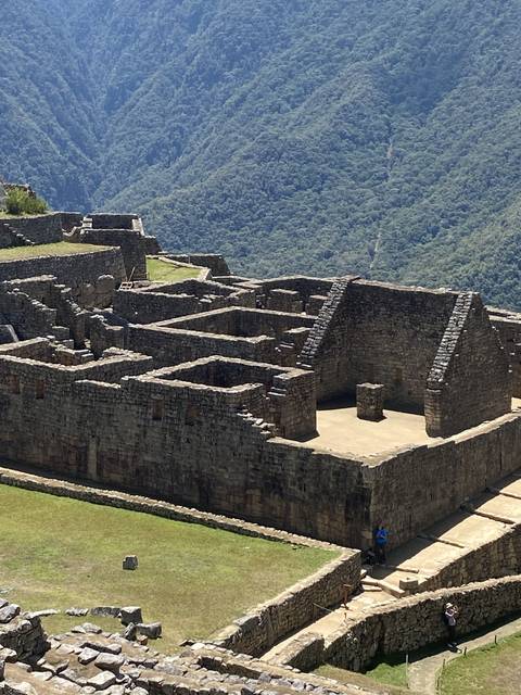 Ancient stone ruins with terraces and mountains in the background.