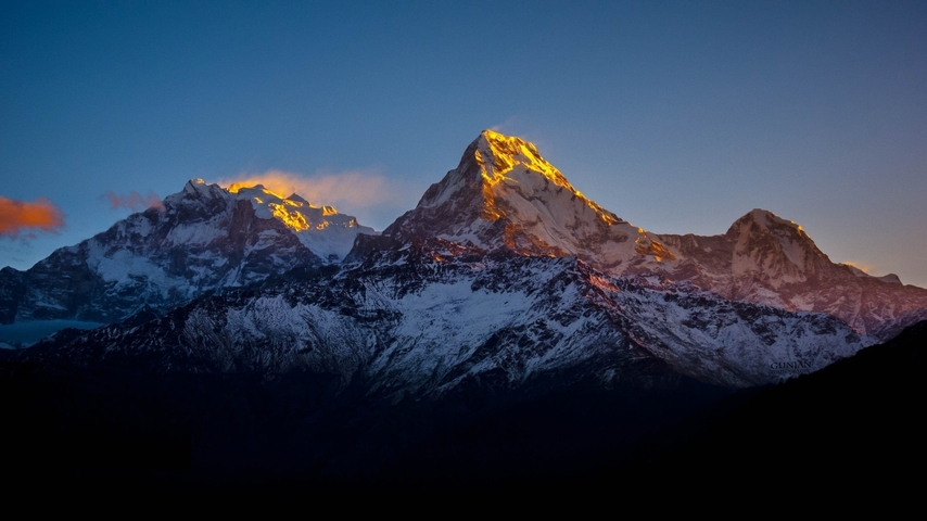 Mountain peaks with snow under a dramatic sky.