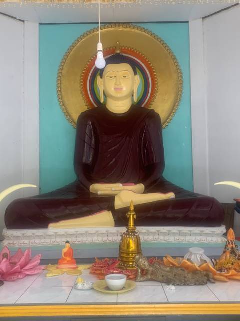 Statue of a sitting Buddha with colorful background details.
